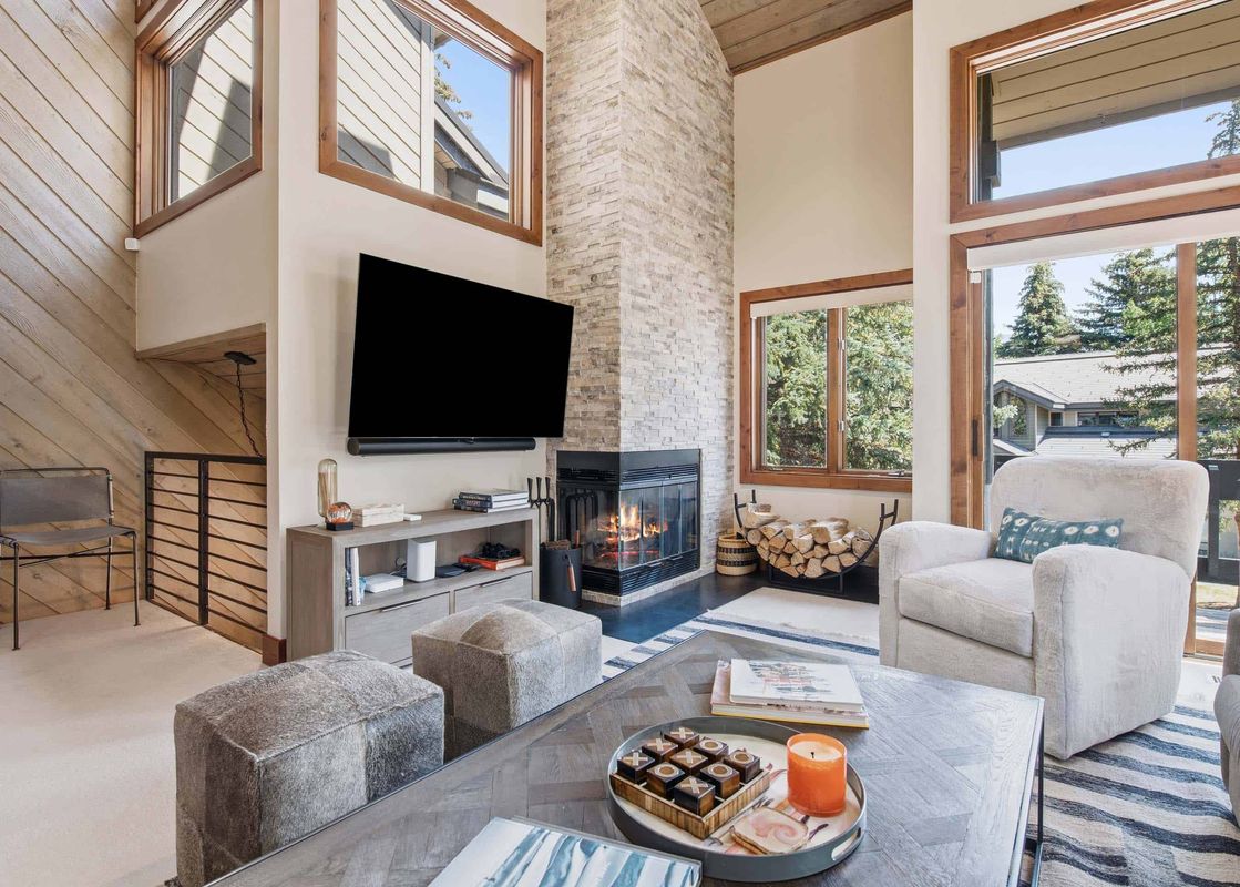 Living room at Ridgepoint Townhome 166 with a stone fireplace and large windows.