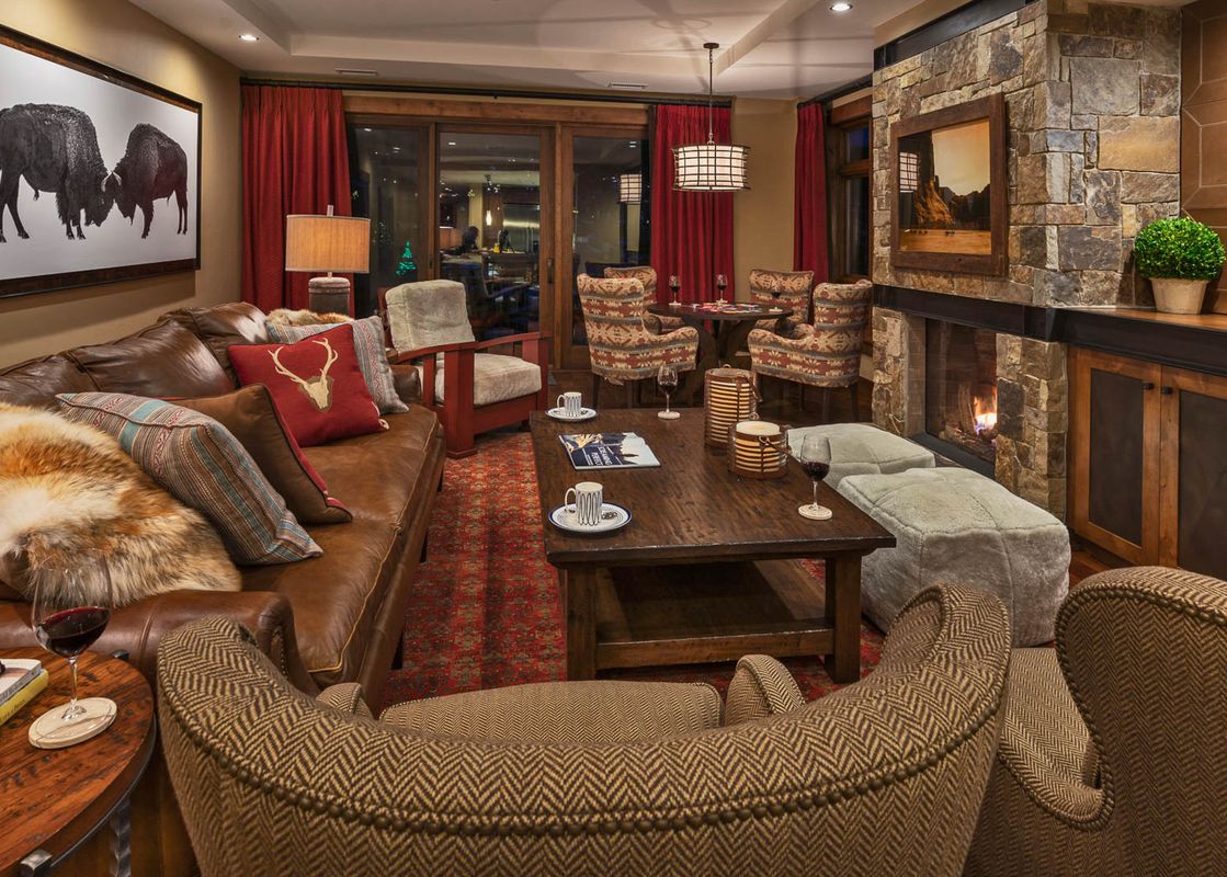 The inviting living area features plush seating, a stone fireplace, and a dining nook.