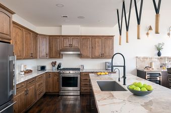 Modern open-concept kitchen in the 5th Street Penthouse featuring wood cabinetry, stainless steel appliances, and a marble island.