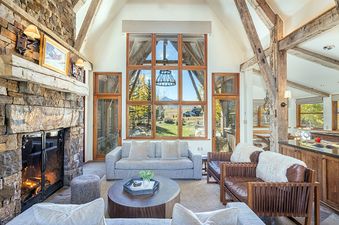 A living room with a stone fireplace and a large window with a view of a mountain.