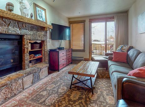 EagleRidge Lodge 211 living room featuring a fireplace and a window offering a view of the surrounding nature.