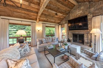 A cozy, rustic-chic living room in Shooting Star Cabin 05 with a stone fireplace, wood-beamed ceiling, and comfortable seating.