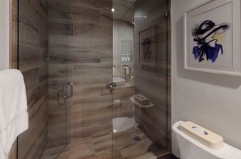 The bathroom in Manor Vail 165 features a walk-in shower with tile walls and a white toilet with a tissue box.