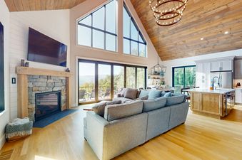 An inviting living space with a fireplace, large windows, and comfortable seating at We Will Ski.