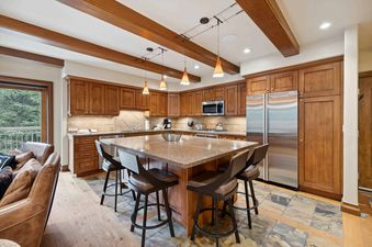 A modern kitchen with wood cabinets, stainless steel appliances, and a large island with bar stools.