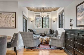 The lounge at Cache at Silver Lake 12 features a cozy seating area with armchairs and a unique wooden coffee table, illuminated by a chandelier and wall sconces.