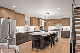 The modern kitchen at Bluebird Chalet Park City features a large island with barstools, sleek two-tone cabinetry, and stainless steel appliances.