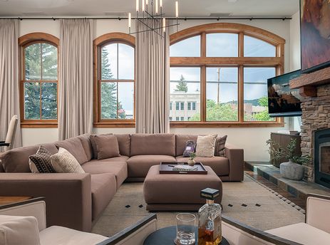 Inviting living room at the 5th Street Penthouse featuring a large sectional sofa, a stone fireplace, and tall arched windows.