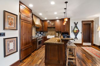 A rustic-inspired kitchen in Arrowleaf Lodge 211 with rich wooden cabinetry, granite countertops, and modern appliances.
