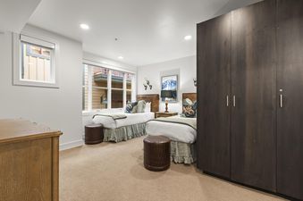 A cozy bedroom in Rio Grande 203 with two twin beds, dark wood wardrobe, and a window view of the building's exterior.