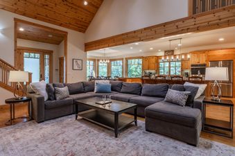 A wide shot of Northstar Sierra Gold Home's open-plan living room and kitchen, featuring a large sectional sofa, coffee table, and dining area.