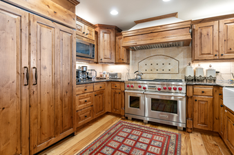 The kitchen in Grand Lodge Three Bedroom Deluxe 407 features a modern stainless steel oven and refrigerator,  wood cabinets, granite countertops, and a large kitchen island.