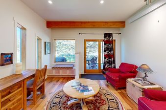 A cozy, beautifully styled living area at Eagles Rest 5 featuring red armchairs, wooden furniture, and views of the outdoors.