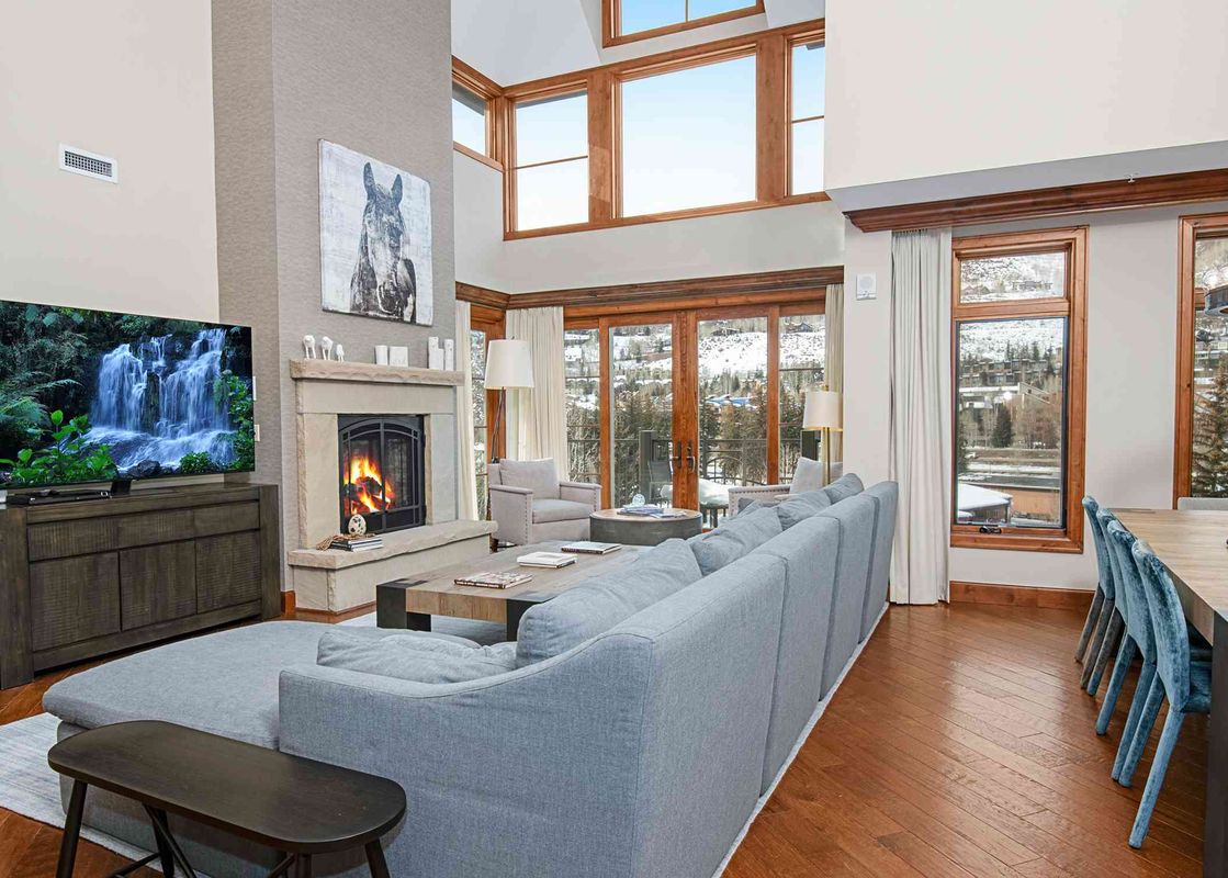 The living room of Ritz Carlton Vail 402, featuring a large sectional sofa, a fireplace, and a large window with mountain views.
