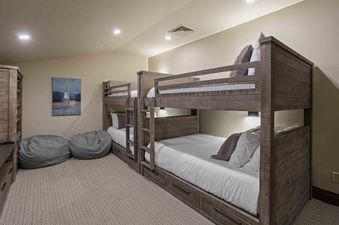 A cozy bunk room at Silver Strike Lodge 706 with two wooden bunk beds, grey bean bag chairs, and a modern art piece on the wall.
