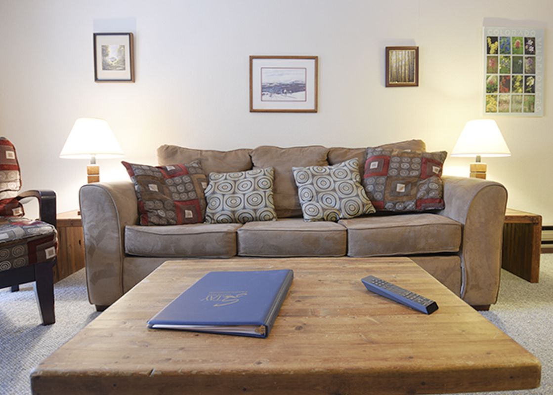The living area at Beaver Village 1821 features a comfortable sofa with throw pillows, two end tables with lamps, a coffee table, and various wall decor.