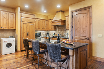 The kitchen of Grand Lodge Studio 205 features a granite counter with a breakfast bar and four bar stools, a double-door refrigerator, a stainless steel sink, a dishwasher, and a microwave.