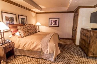A cozy bedroom with a large bed, two bedside tables with lamps, and decorative pillows, offering a warm and inviting atmosphere.