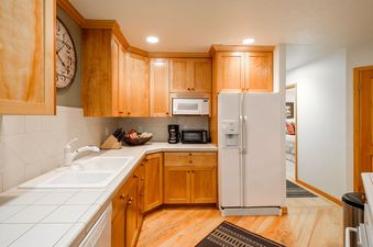 The Deer Lake Village Abode features a cozy kitchen with light wood cabinets and modern appliances.