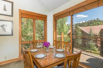 Dining table set for a meal next to large windows showing scenic mountain views at Lynx at the Terraces.