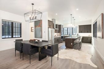 A modern dining room and kitchen with dark wood accents and large windows showing a snowy exterior.