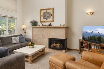 A cozy living room at Vantage Point 504 with a fireplace, television, and mountain views from the window.