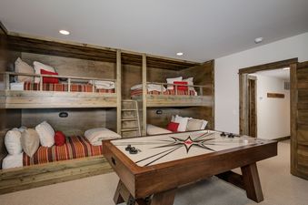 A games room at Homestead Chalet 8 Claim Jumper featuring built-in bunk beds with colorful bedding and an air hockey table in the center.