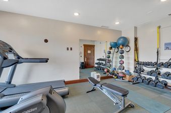 The private fitness center at Guardsman Overlook features a treadmill, free weights, an adjustable bench, and fitness balls, all set against a mirrored wall with recessed lighting.