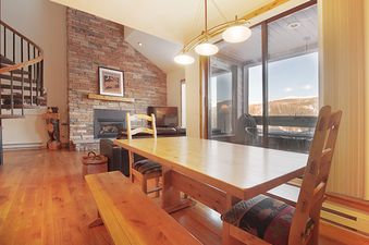 The Snowblaze A33 dining area with a wooden table, bench, and chairs, and a fireplace in the background.