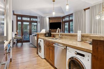 The kitchen in The Aspen 03B features a full-size washer and dryer, stainless steel appliances, and a beautiful granite countertop.