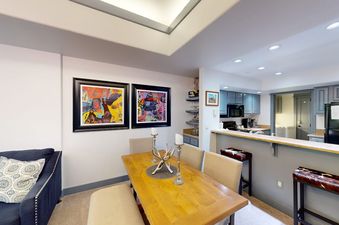 Dining area with a wooden table, artwork on the wall, and adjacent kitchen breakfast bar at Canyon Creek B304.