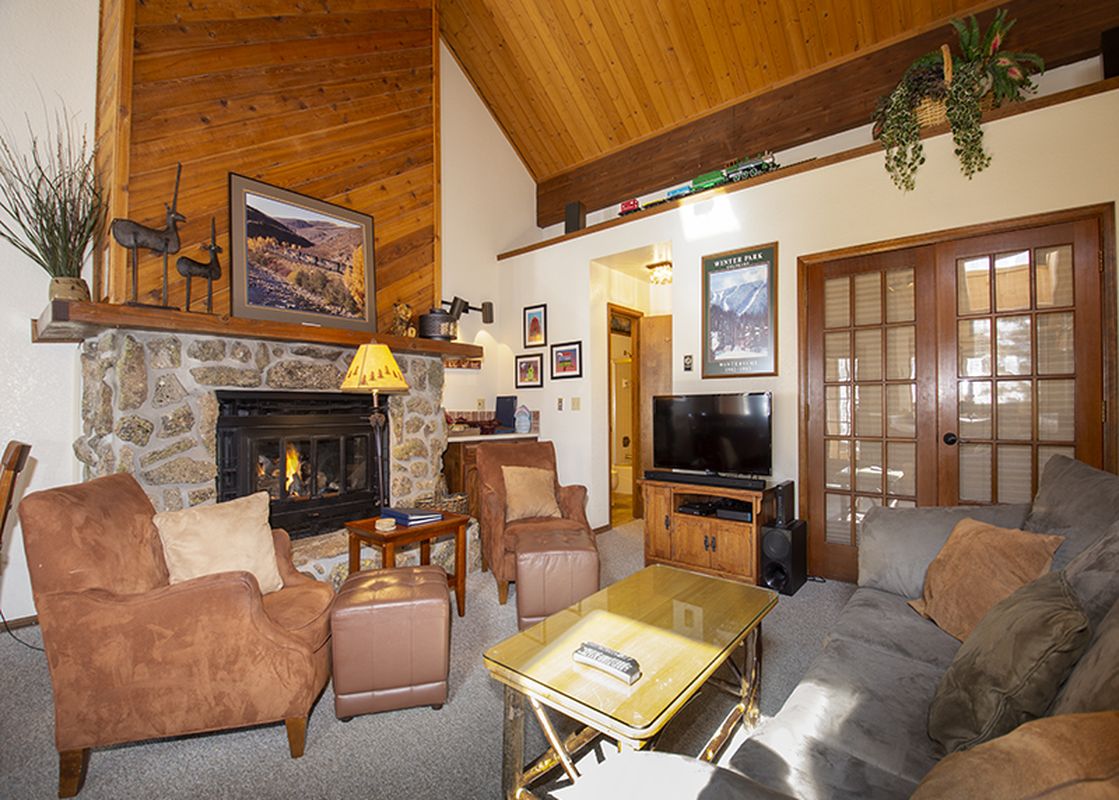 The living area of Kings Crossing Townhome 4 features a stone fireplace, comfortable seating, and a vaulted wooden ceiling, creating a warm and inviting atmosphere.