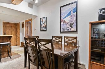 A dining room table with four chairs, set with a wooden table and a wood and glass cabinet in the background.