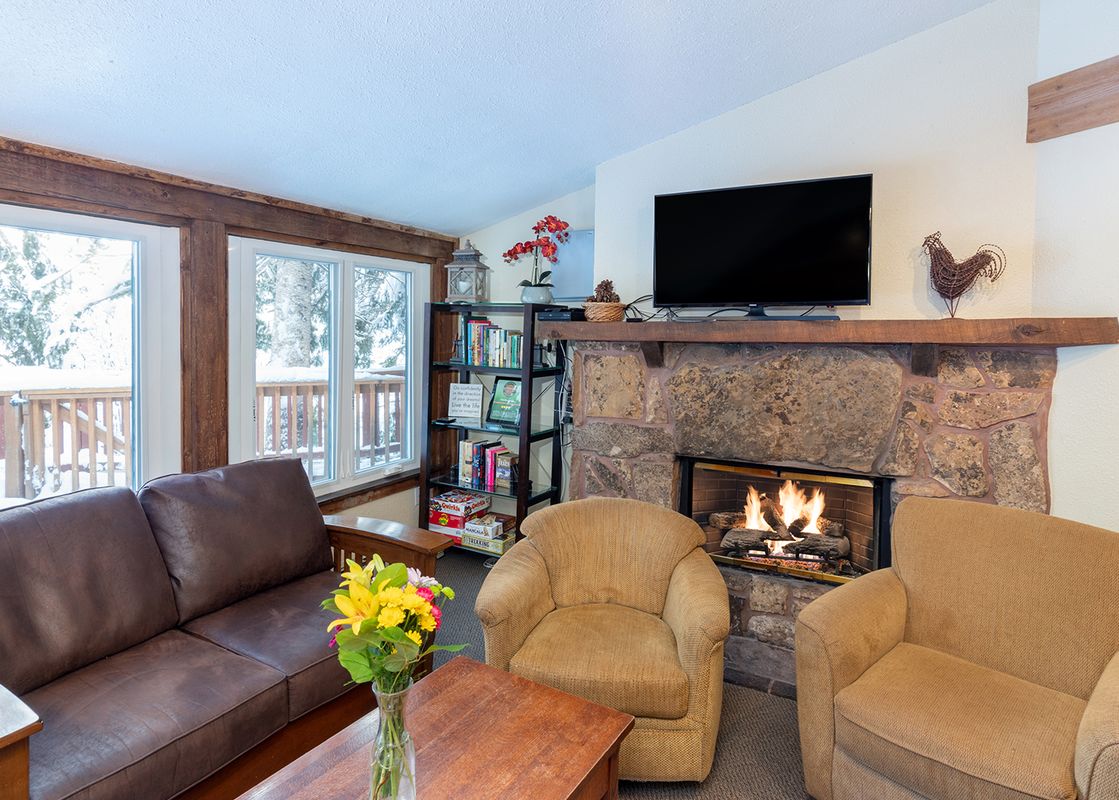 The cozy living room in Manitou Lodge 9 invites relaxation with its warm fireplace and comfortable seating.