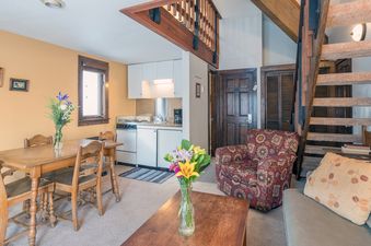The interior of Manitou Lodge 7 features a dining table, kitchen, living area, and stairs to the loft.