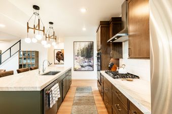 Modern kitchen with wood cabinets, light countertops, a spacious island, and upscale stainless steel appliances in Deer Valley East Above and Beyond.