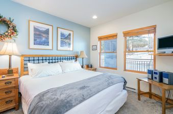 The bedroom at Bear Creek Lodge 302 has a king bed, large windows, and a wooden dresser.