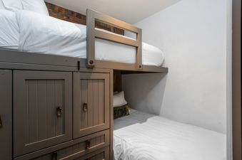 The bunk beds in Bridge Street Lodge 2 Bedroom Diamond Unit 306 are designed for comfort, featuring crisp white bedding on both the upper and lower berths, with a vibrant 'WELCOME' pillow adding a touch of hospitality.