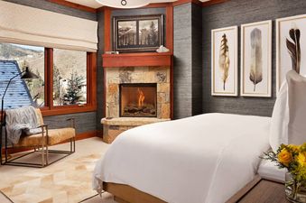Cozy bedroom with a stone fireplace, large bed, and mountain view window at The Star Two Bedroom Residence.
