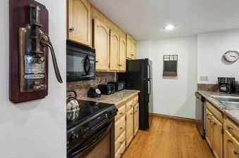 The kitchen in Lodge Tower 487 3 Bedroom features black appliances and light wood cabinets.