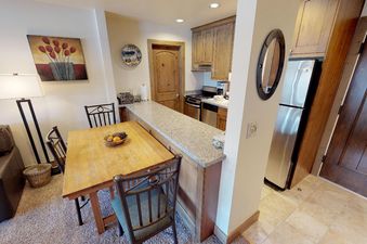 The kitchen in Manor Vail 276 is well-equipped with a stainless steel refrigerator and other appliances, along with a breakfast bar with seating.