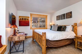 Charming bedroom featuring a wooden bed frame and bedside table, complemented by a rustic desk.