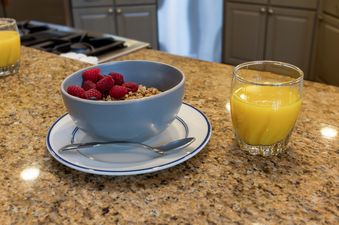 A healthy breakfast of granola and berries beside a glass of orange juice.