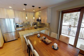 The kitchen in Manor Vail 254 is spacious with stainless steel appliances and a large dining table