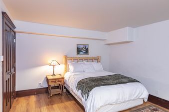 A bedroom with a double bed, a nightstand, and a lamp.