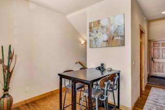 A dining area with a small table and chairs, a black dog statue, and a piece of artwork on the wall.