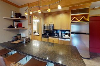 A kitchen with stainless steel appliances and dark granite countertops.