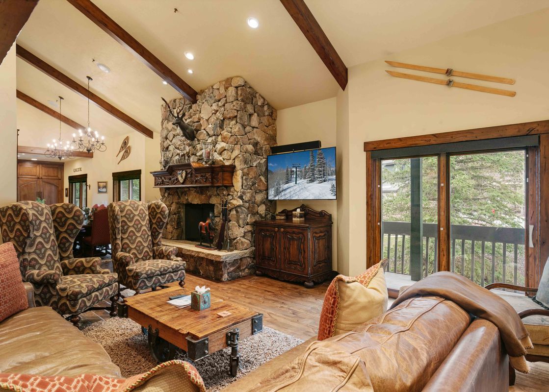 The cozy living room at Lakeside 1617 invites relaxation with its stone fireplace, comfortable seating, and rustic decor.