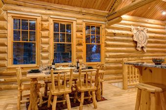 The dining area of Obsidian Jackson Hole with a wooden table, chairs, and log cabin walls.