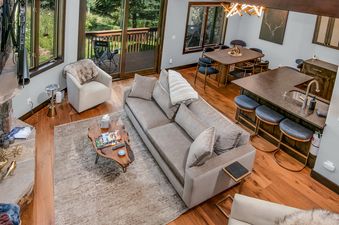 A wide, elevated view captures the sophisticated open-concept living space of Chateau Tremonte 8, featuring a comfortable living room, a modern dining area, and a sleek kitchen with a central island.